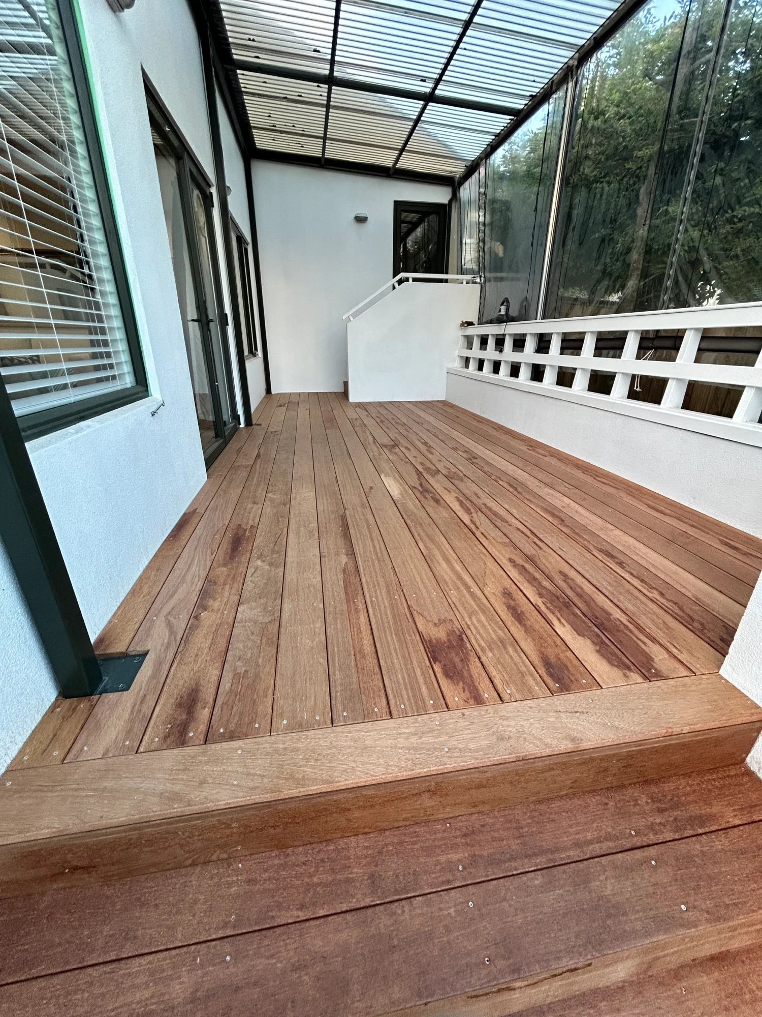 Covered hardwood deck with clear roof by LSM Construction